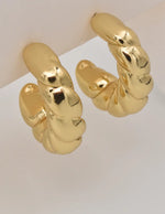 Close-up of dangle earrings with sculptural rope texture