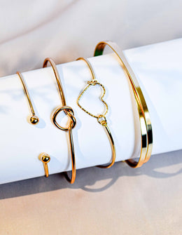 Set of gold charm bracelets with heart and knot details