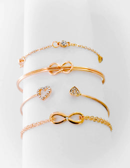 Infinity charm bracelet in gold paired with heart ring and chain