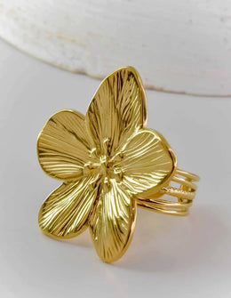 Golden floral ring with detailed petal etching shown on light surface