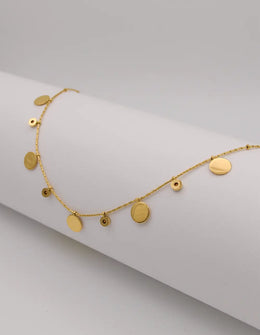 Dainty gold necklace with hammered coins and zircon drops on white background
