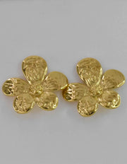 Gold flower earrings with hammered petal texture on neutral backdrop


